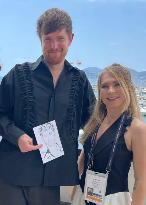 James Blake holding his live portrait beside Adriana in Cannes
